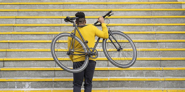 Mann trägt sein Fahrrad die Treppen hoch