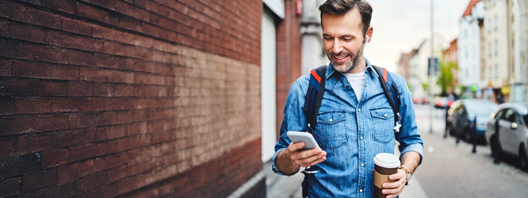 Ein Mann öffnet informiert sich an seinem Smartphone über die Servicekarte der Öffentlichen Versicherung Braunschweig