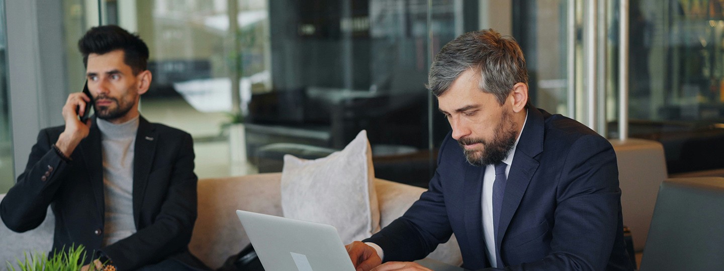 Zwei Kollegen: Einer telefoniert, der andere arbeitet am Laptop