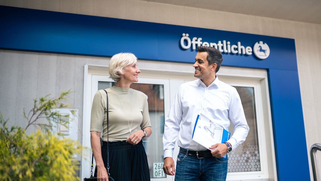 Berater mit Kundin vor einer Geschäftsstelle der Öffentlichen Versicherung Braunschweig