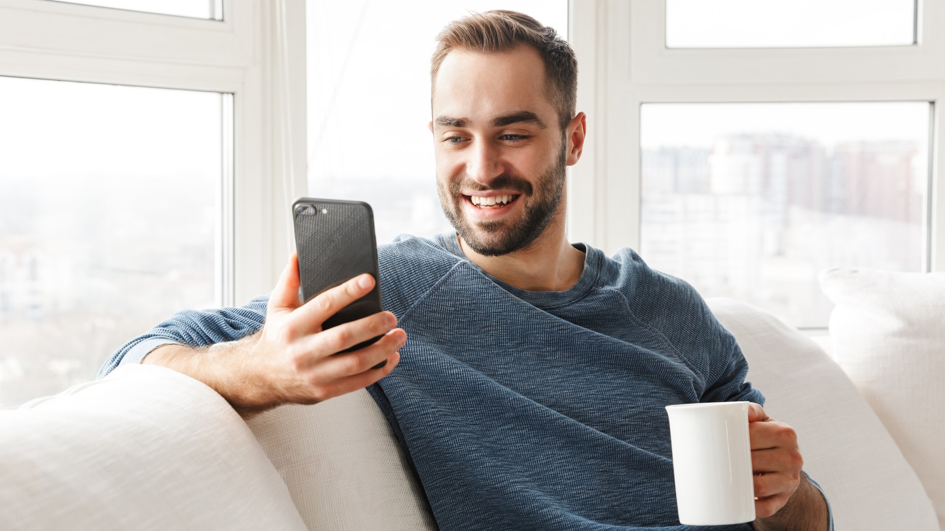 Mann schaut in sein Smartphone und freut sich über seinen BraunschweigTresor
