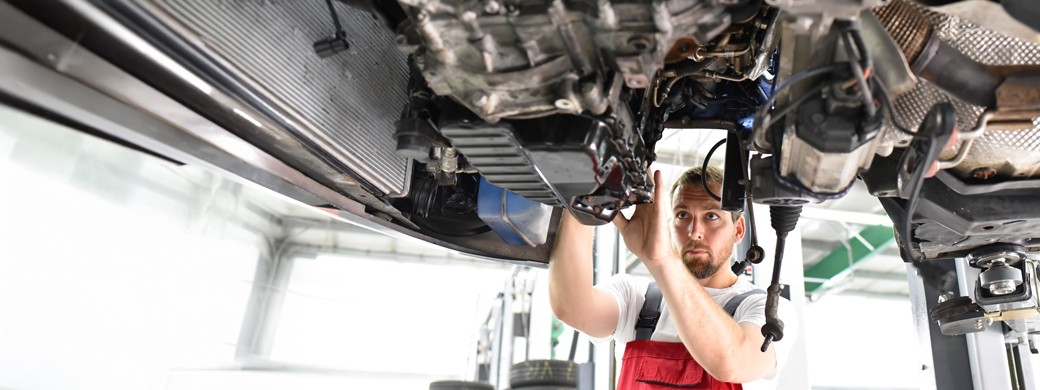 Mitarbeiter begutachtet Schaden am Heck eines Autos