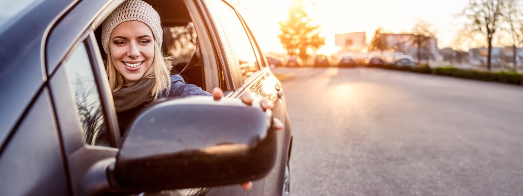 Kundin der Öffentlichen sitzt im Auto und schaut in den Seitenspiegel