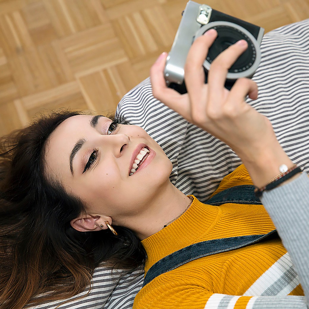 Junge Dame mit liegt auf dem Sofa mit einer Kamera in der Hand