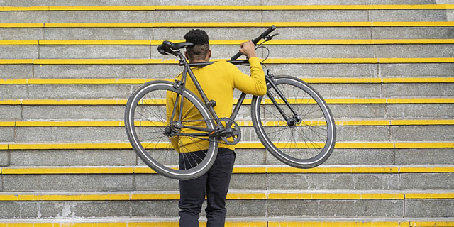 Mann trägt sein Fahrrad die Treppen hoch