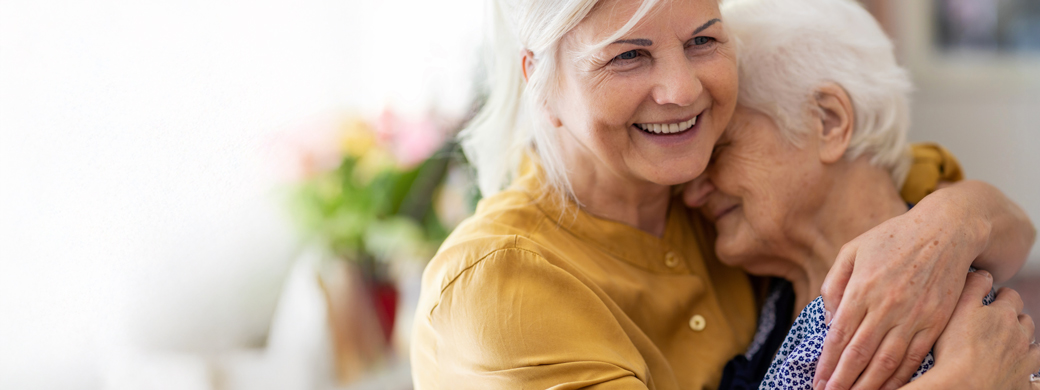 Ältere Kundin der Öffentlichen umarmt ihre Mutter beim Besuch im Pflegeheim