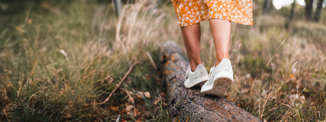 Frau balanciert auf einem Baumstamm