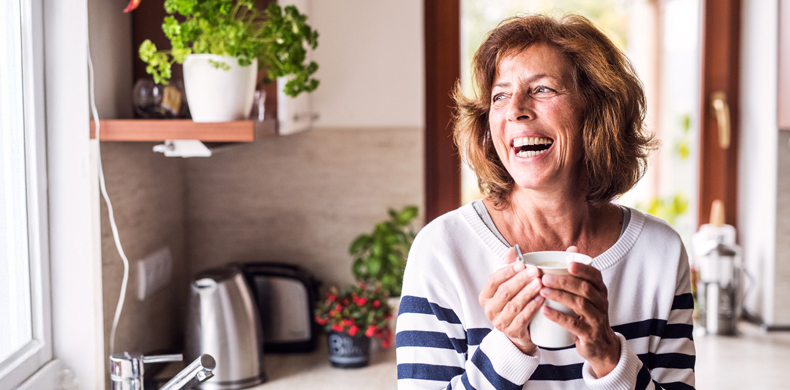 Bauherrin in der Küche lacht mit Kaffee-Tasse in der Hand