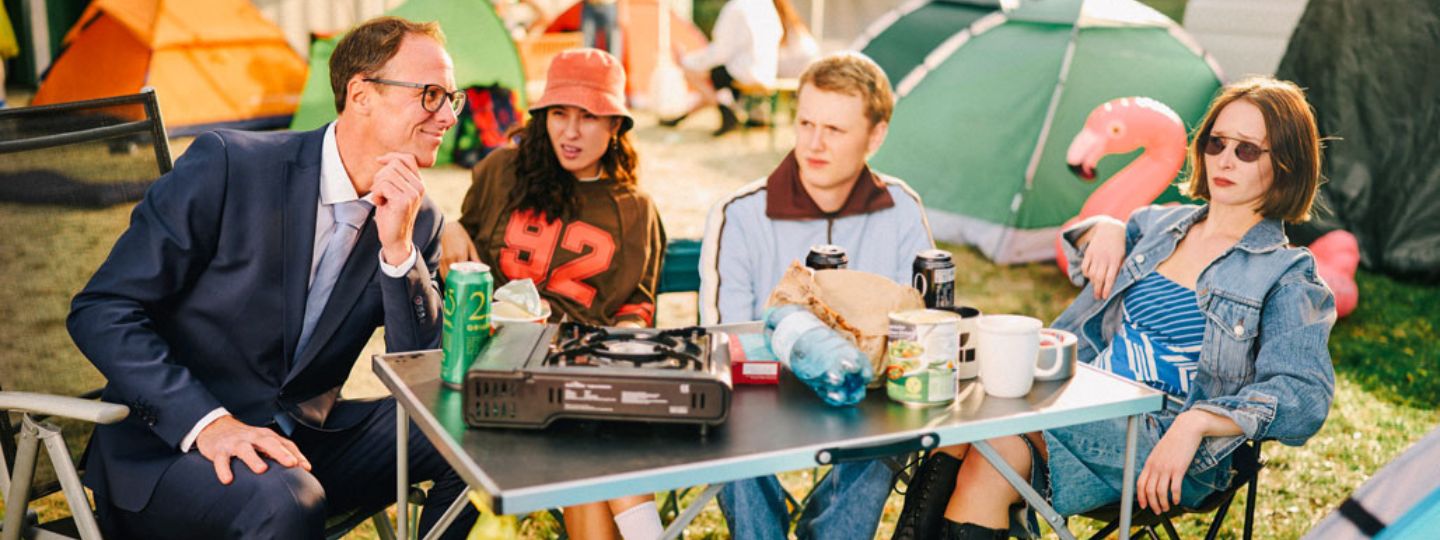 Berater der Öffentlichen sitzt mit jungen Erwachsenen am Tisch auf einem Campingplatz