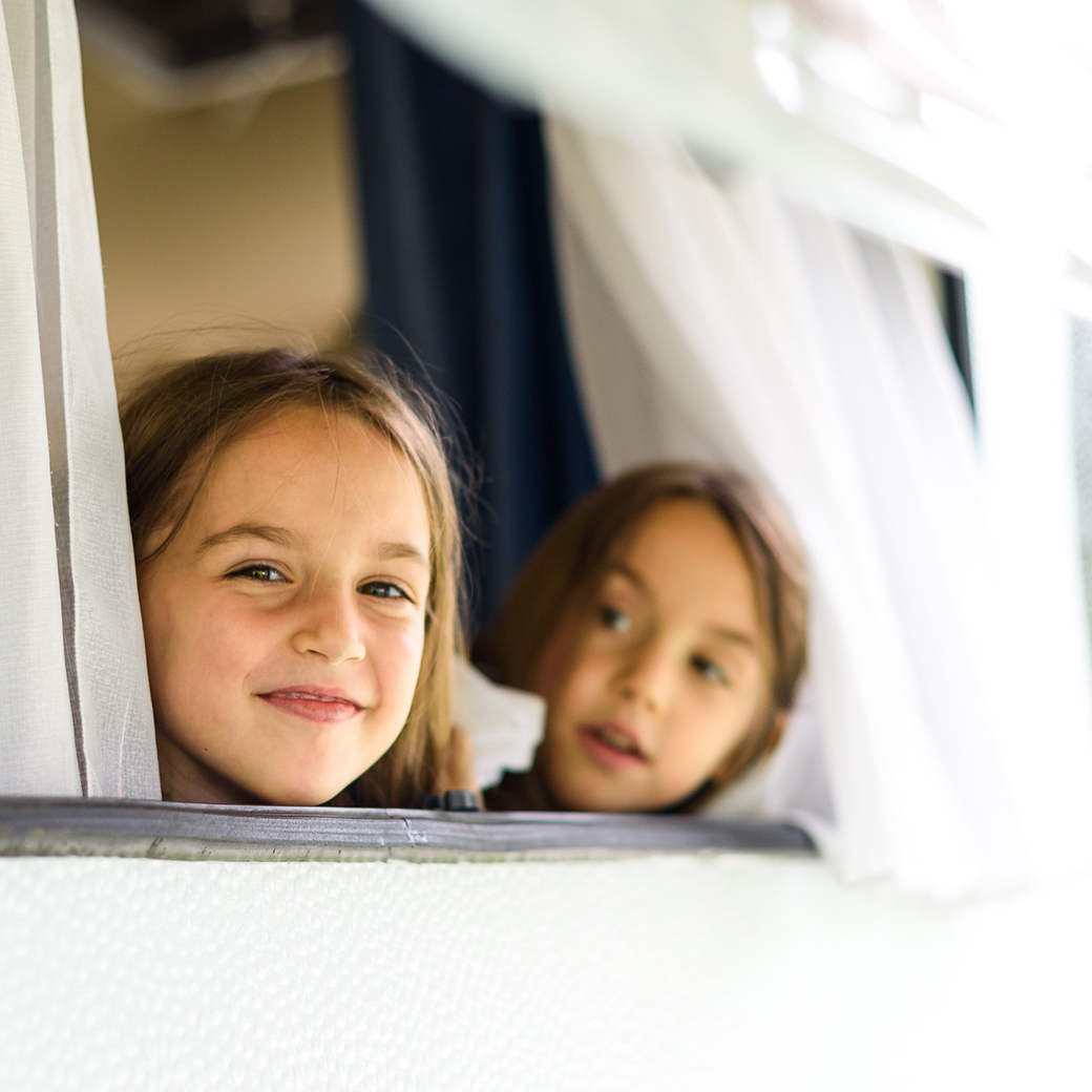 Kinder schauen aus Fenster eines Wohnmobils