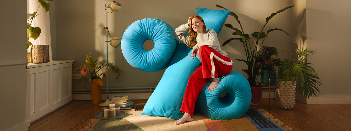 Kundin der Öffentlichen Versicherung Braunschweig sitzt bequem auf einem Kissen in Form eines Prozentzeichens