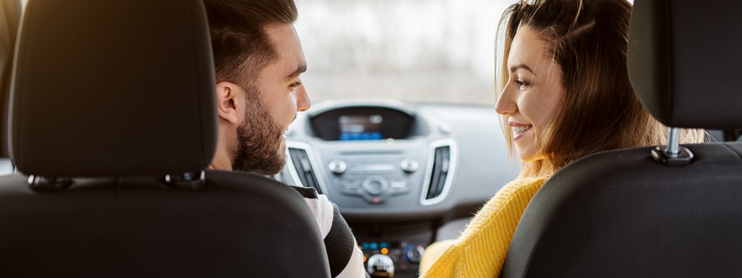 Pärchen sitzt im Auto und lächelt