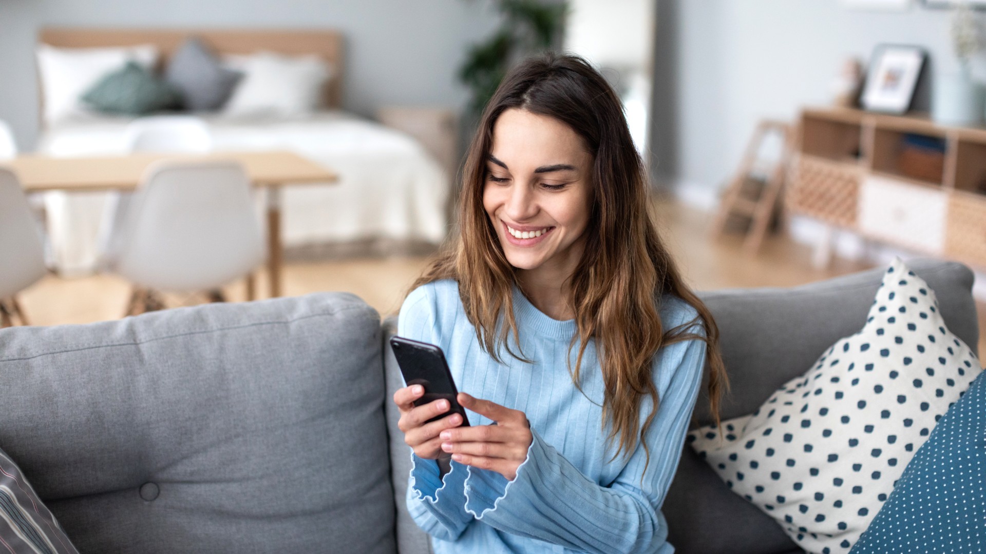 Kundin der Öffentlichen informiert sich via Handy zu wichtigen FAQ rund um ihre Versicherung