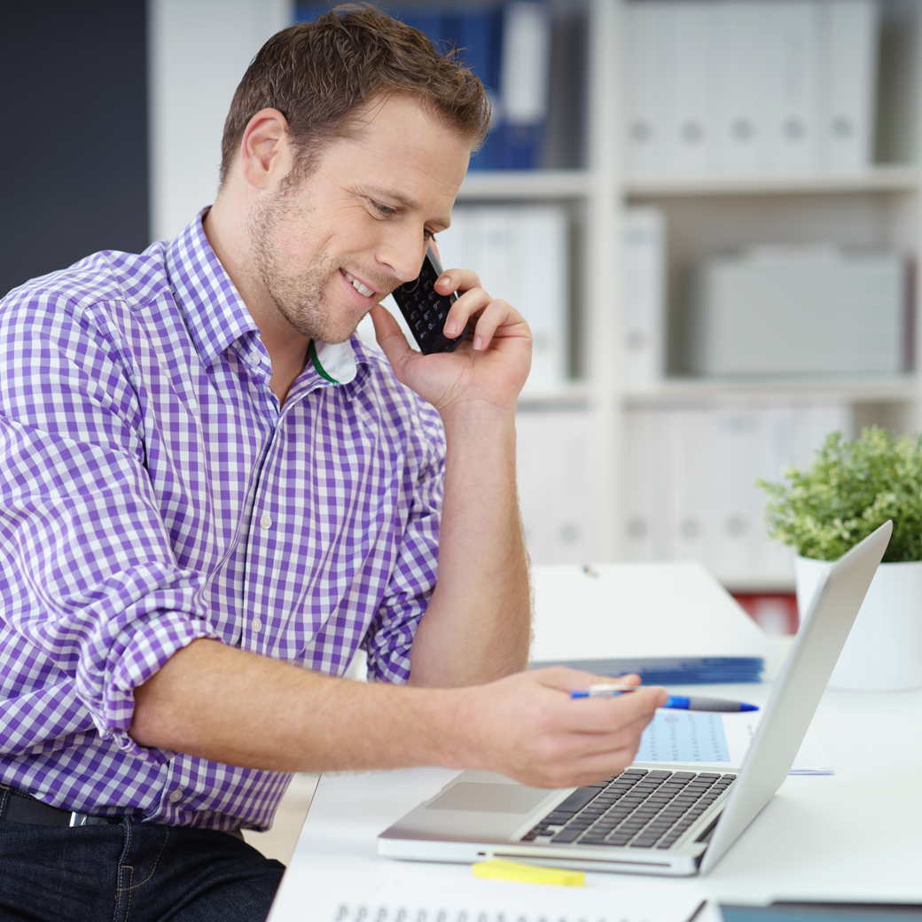 Ein Mitarbeiter ist am arbeiten und telefoniert dabei mit einem Kunden