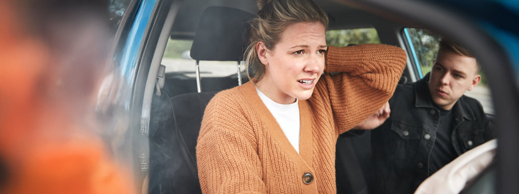 Frau nach einem Autounfall sitzt auf dem Beifahrersitz im Auto neben ihrem Mann