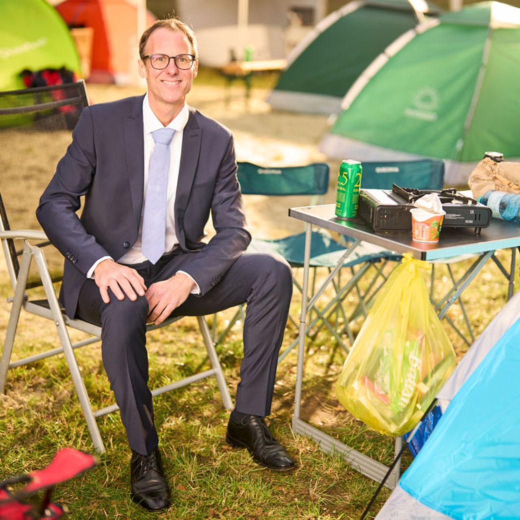 Berater der Öffentlichen sitzt lächelnd am Campingtisch