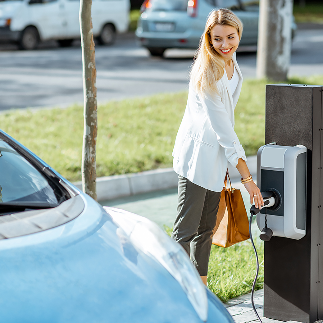 Frau lädt ihr E-Auto auf