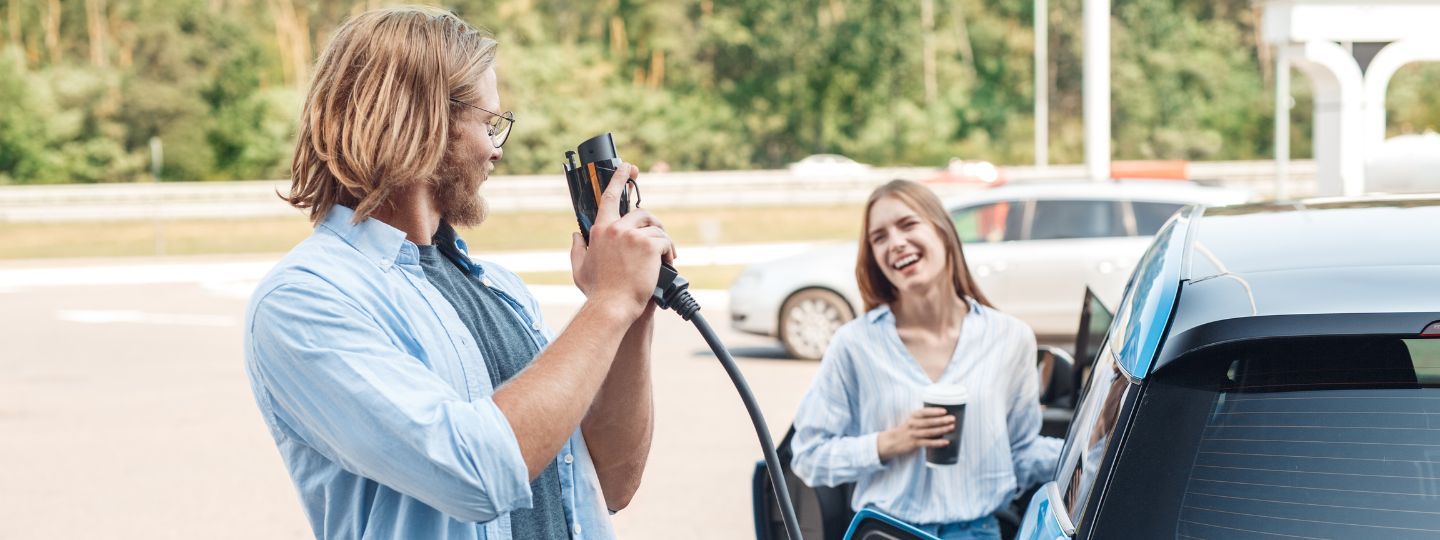 Mann und Frau an einer E-Ladesäule mit ihrem Auto