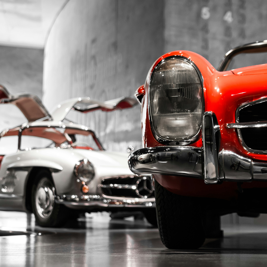 Angeschnittene Aufnahmen zweier Oldtimer auf einer Ausstellungsfläche