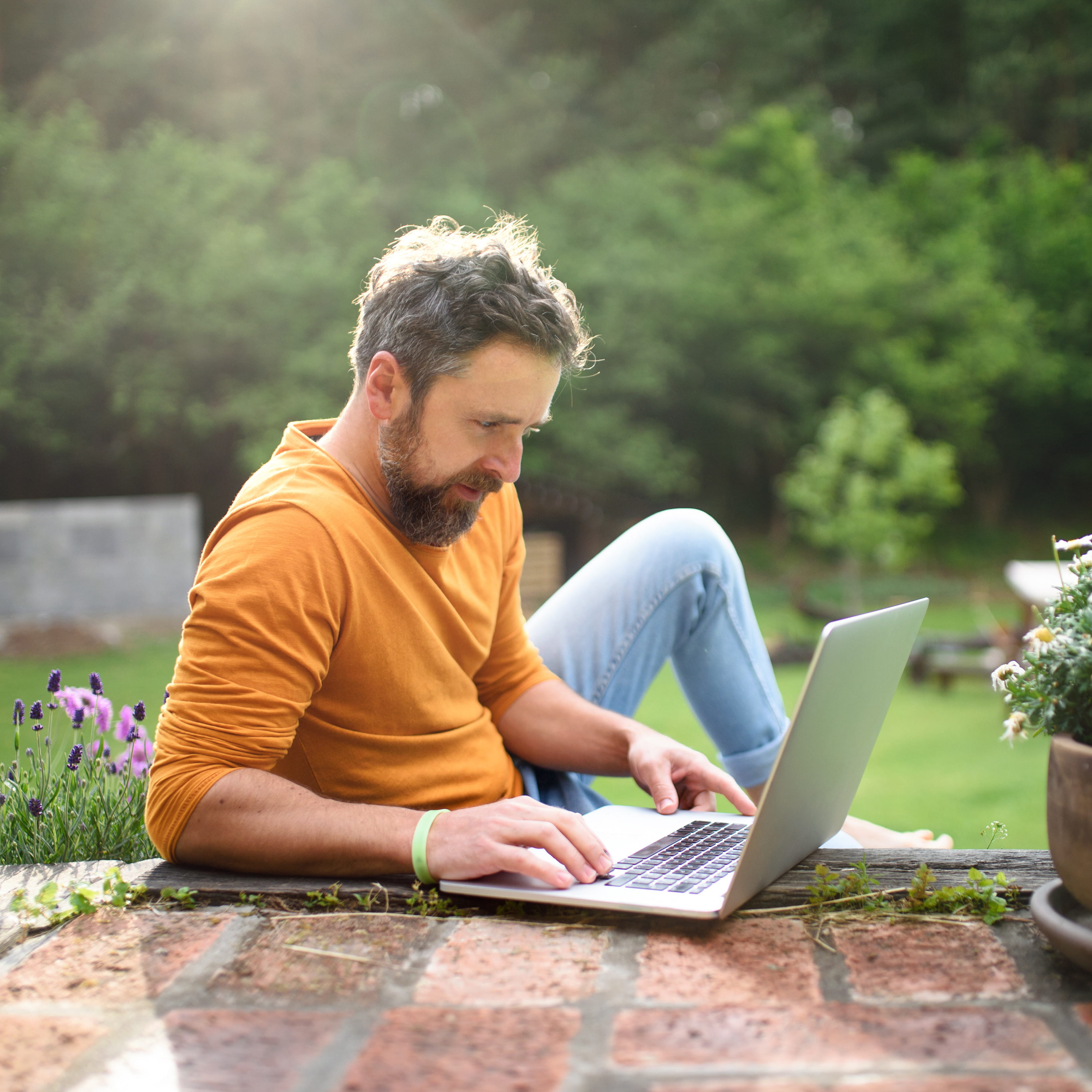 Mann schaut auf seine LöwenRente Klassik auf seinen Laptop im Garten