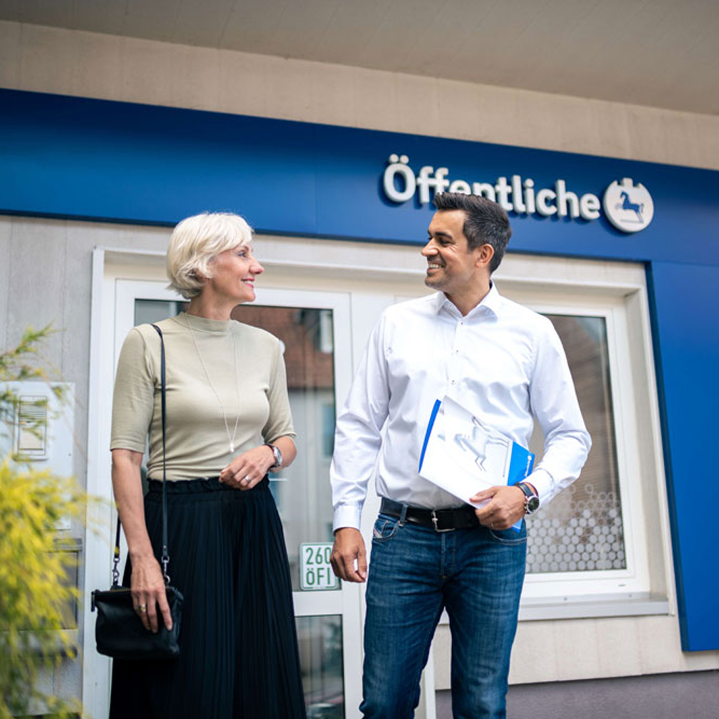Ein Berater im Austausch mit einer Frau vor einer Außenstelle der Öffentlichen