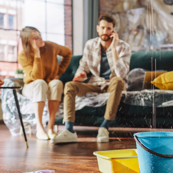 Ein Pärchen sitzt auf dem Sofa und der Mann telefoniert mit dem Handwerkerservice der Öffentlichen