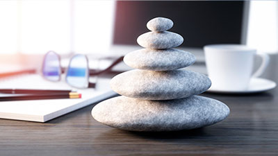 Symboldbild mit gestapelten Steinen auf Büro-Schreibtisch für Benefits bei der Öffentlichen Braunschweig: Work-Life Balance
