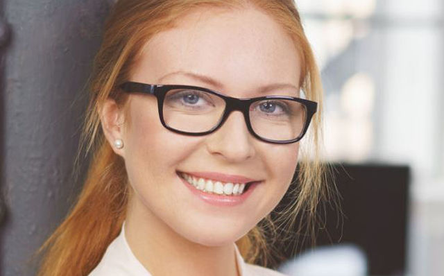 Lächelnde Frau mit roten Haaren und Brille