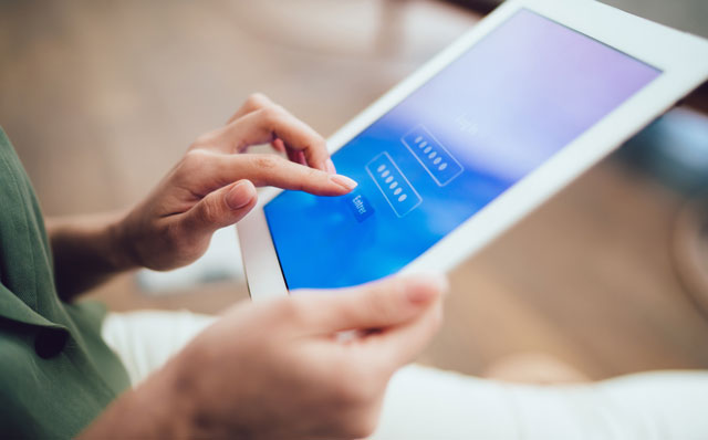Ein Tablet mit einem blauen Bildschirm in den Händen einer Person.