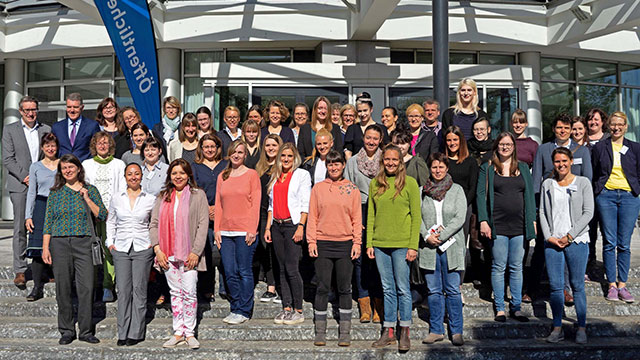 Eine Gruppe, vorwiegend Frauen, steht vor dem Haus der Öffentlichen auf der Treppe, ein klassisches Gruppenfoto