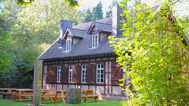 Ein schönes Fachwerkhaus im Grünen mit Sitzgelegenheiten auf der Wiese.