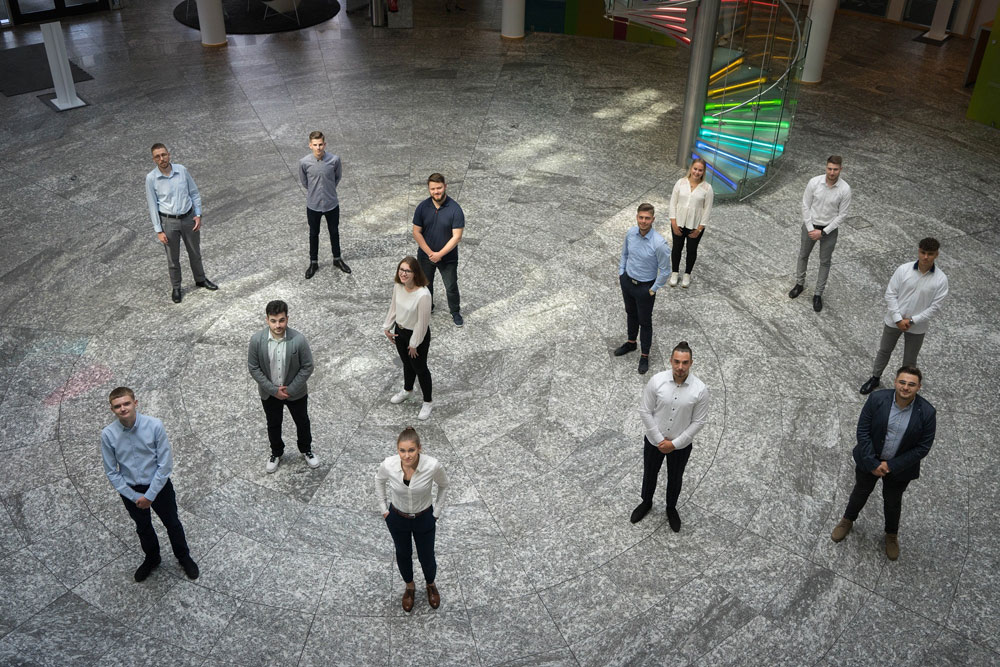 Zwölf junge Menschen von oben fotografiert im Bürogebäude der Öffentlichen Versicherung