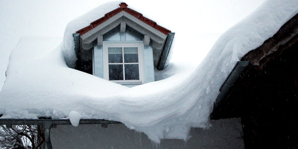 Ein Hausdache auf dem sehr viel Schnee liegt