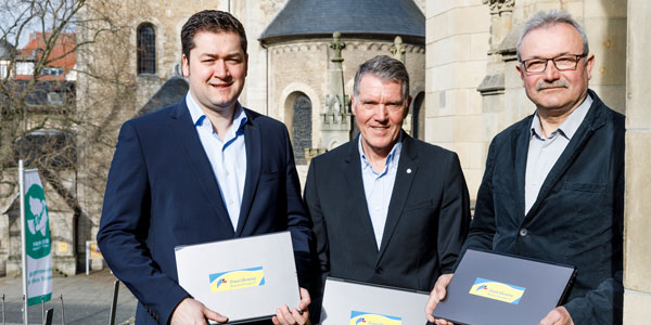 Drei männliche Personen stehen vor einem Gebäude, sie halten je ein graues Notebook in den Händen. Es sind Braunschweigs Oberbürgermeister Dr. Thorsten Kornblum, Knud Maywald, Vorsitzender des Vorstandes der Öffentlichen, und Igor Piroschik, 1. Vorsitzender des Vereins Freie Ukraine Braunschweig (von links nach rechts)