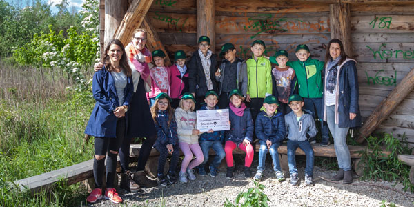 Schulklasse stehen vor einer Holzwand