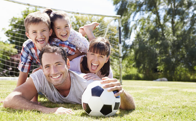 Familie liegen auf dem Rasen - Vater hat einen Fußball in der Hand