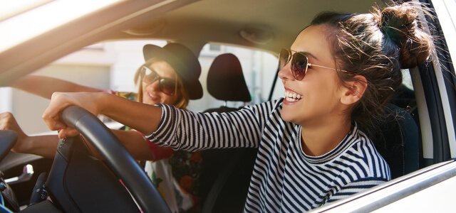 Zwei Frauen lachend im Auto bei öffenem Fenster