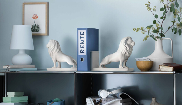 Büro mit  zwei weißen Löwenfiguren und einem blauen Ordner