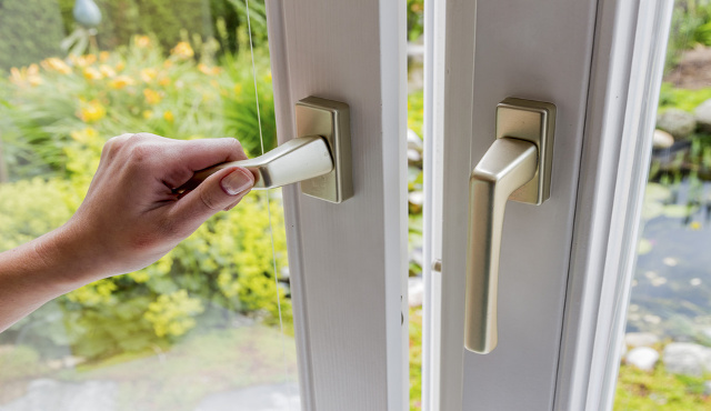 Hand an einem Fenstergriff, Fenster wird geöffnet