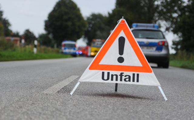 Ein Warndreieck auf einer Landstraße sichert eine dahinter liegende Unfallstelle ab