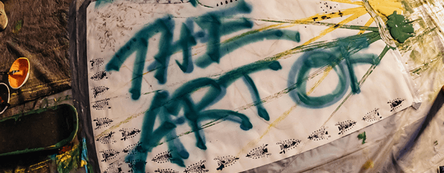 Künstlerischer Schriftzug auf einem Stoffbanner in Graffiti-Optik. Der Schriftzug zeigt die Worte: THE ART OF.