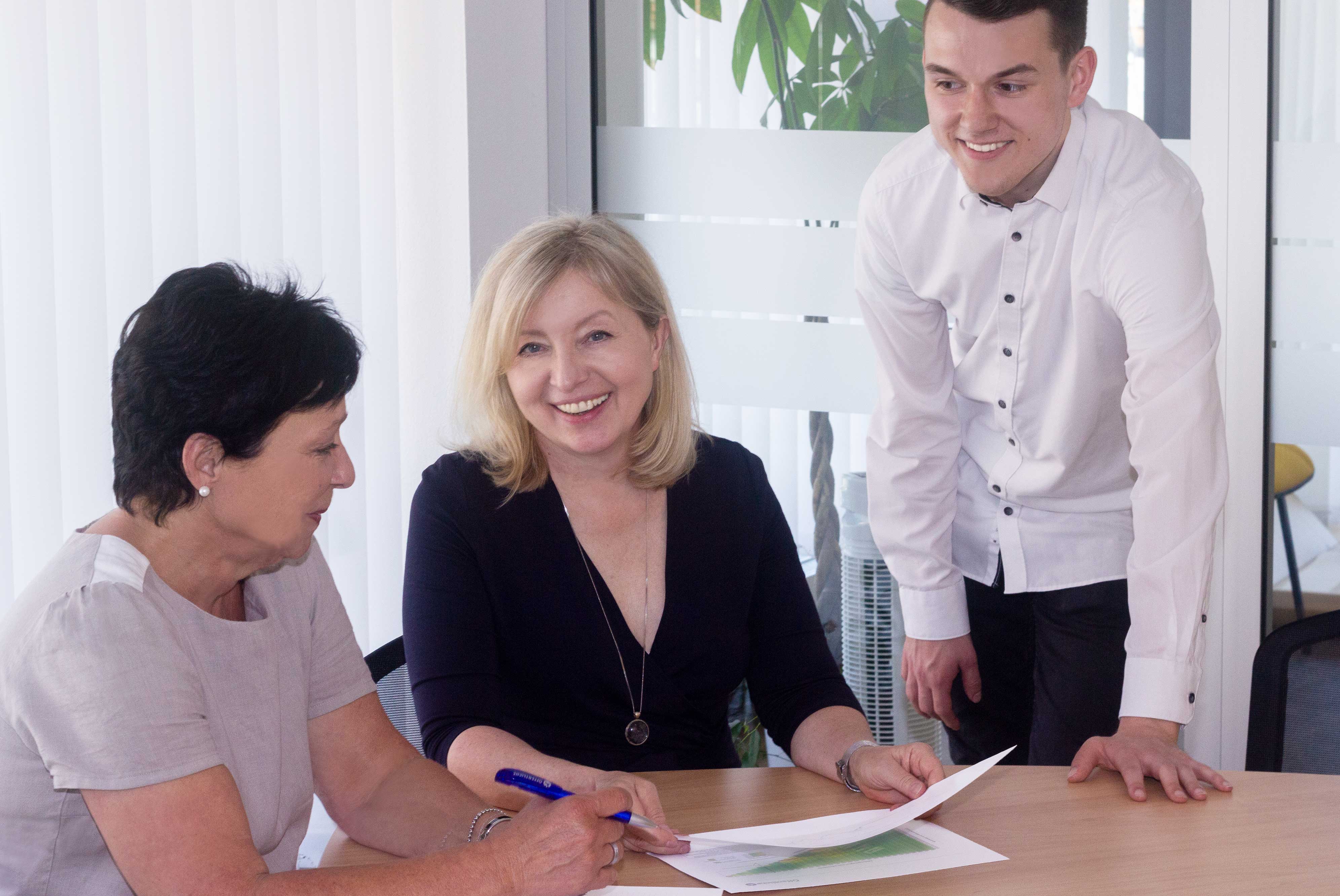 Yvonne Spitzer sitzend im Büro mit zwei weiteren Mitarbeitern