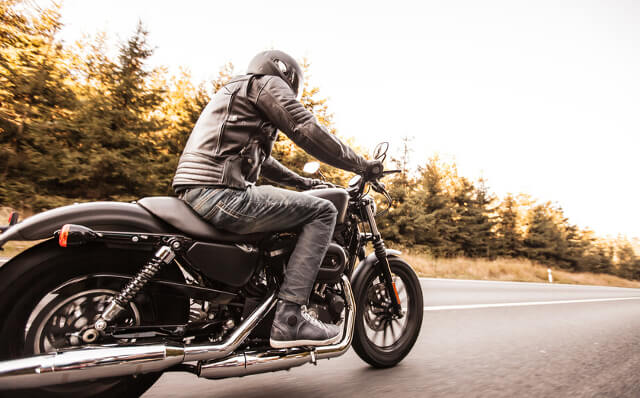 Ein klassisches Motorrad mit Fahrer auf einer Straße.